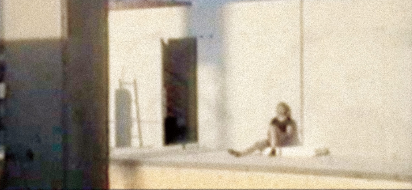 Na zdjęciu kobieta siedząca pod ścianą