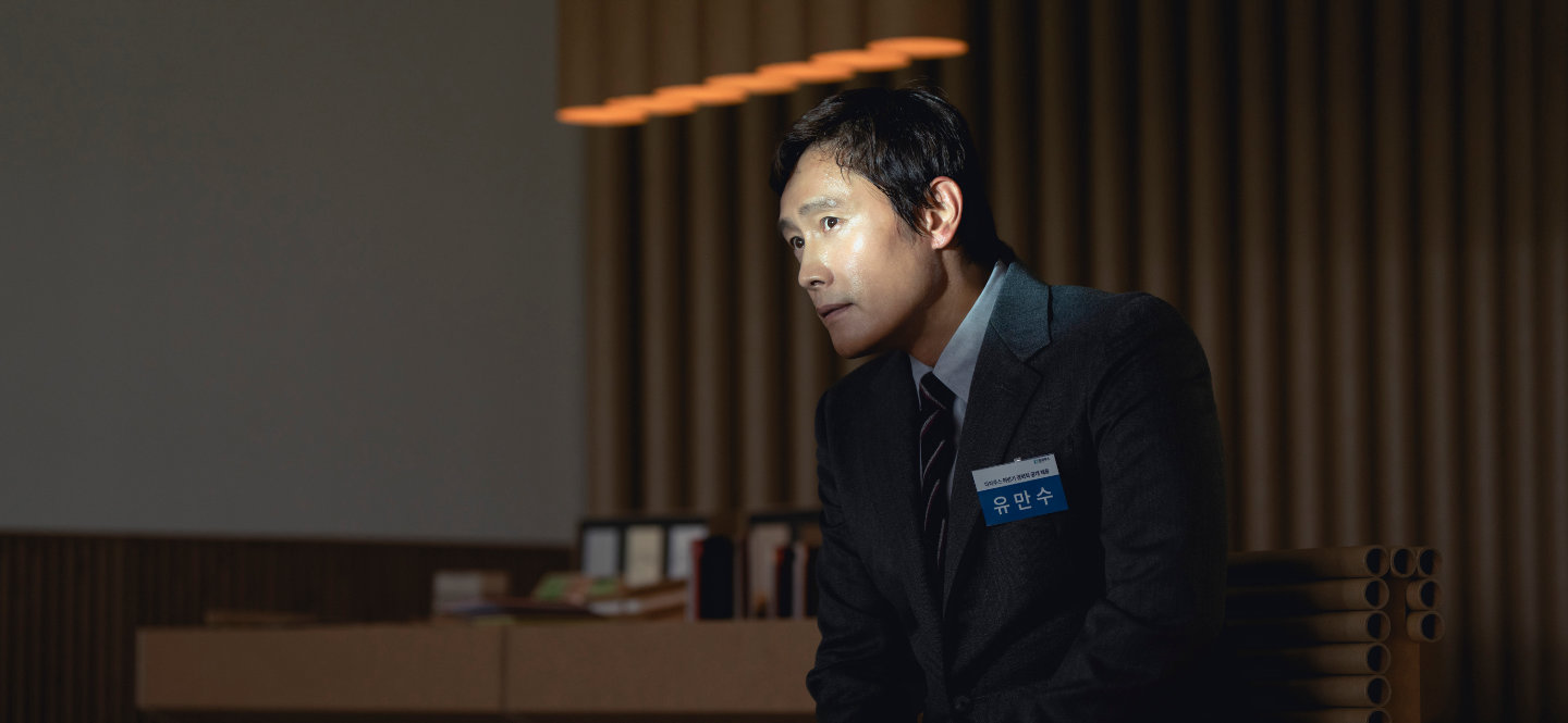 Siedzący mężczyzna z identyfikatorem przypiętym do marynarki.