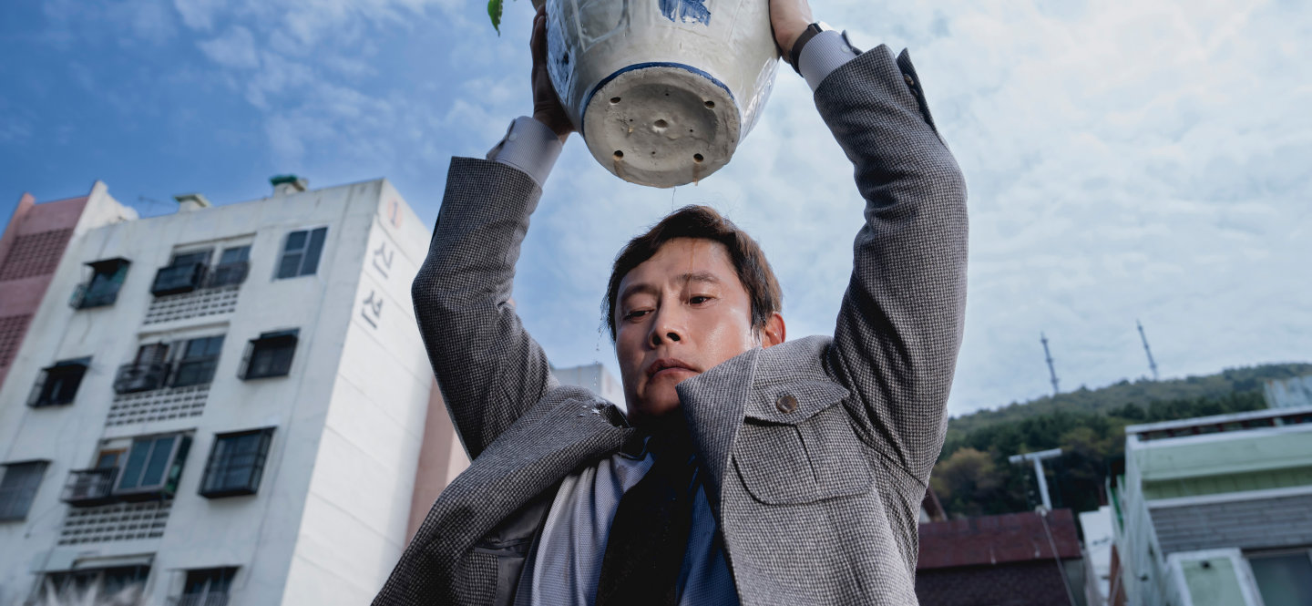 Mężczyzna trzymający doniczkę z kwiatkiem nad głową.