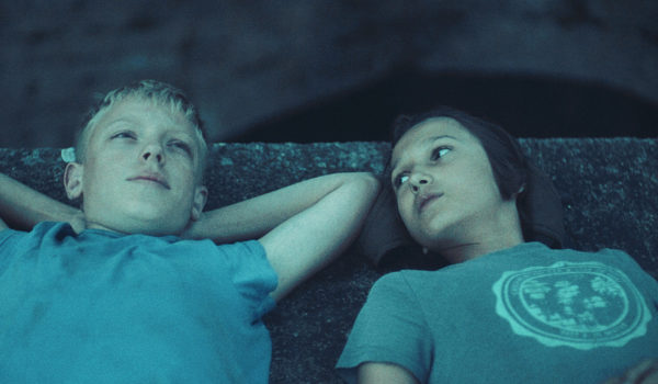 Na zdjęciu dwoje dzieci leżących na betonie.