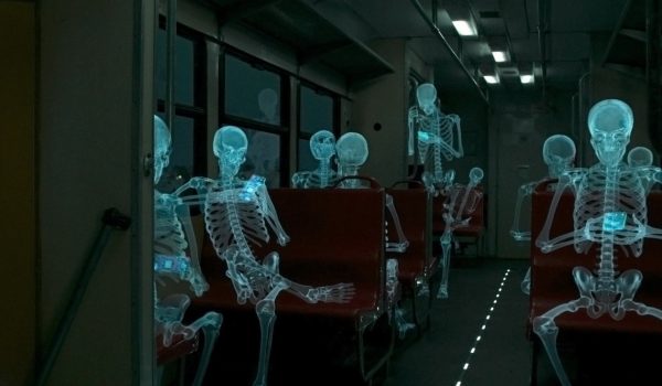 Na zdjęciu postaci ludzi prześwietlone jak na zdjęciu rendgenowskim siedzące w pociągu