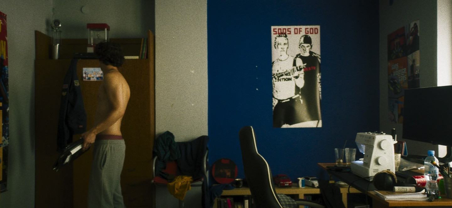 Na zdjęciu pokój z mężczyzną wkładającym ubranie do szafy.
