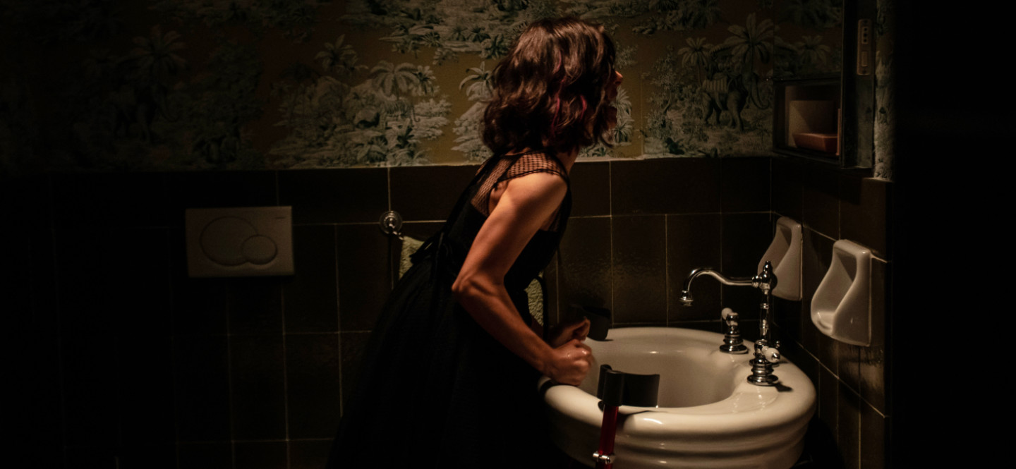 Na zdjęciu kobieta w łazience przeglądająca się w lustrze.