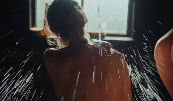 Na zdjęciu kobieta oblewająca się wodą w saunie.