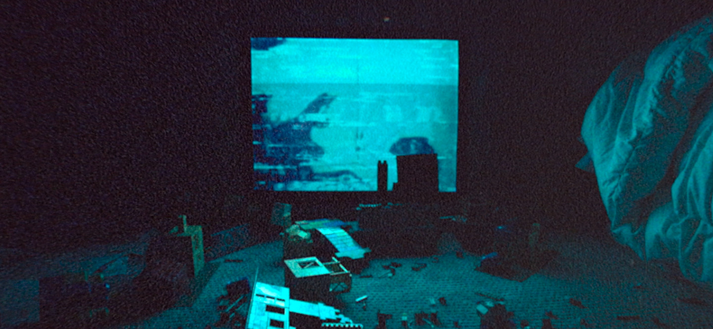 Na zdjęciu ciemny pokój, świecący ekran, na podłodze porozrzucane klocki.